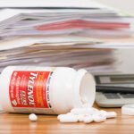 Fosston, USA - February 14, 2011:  A tipped over and spilled bottle of Extra Strength Tylenol Acetaminophen Caplets in front of a pile of paperwork, a calculator, a pen, and the bottle lid.  The Tylenol bottle contains 100 caplets, 500 mg each and is manufactured By: McNeil Healthcare LLC, Las Piedras, Puerto Rico For: McNeil Consumer Healthcare, Division of McNeil - PPC, Inc. Fort Washington, PA, USA